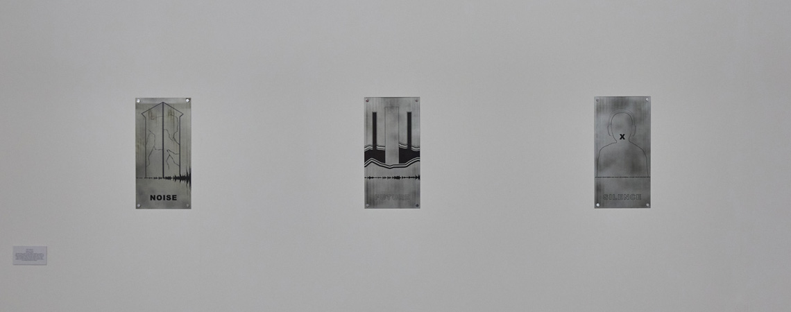 Exhibition of work by student - three rectangular silver plaques on a white background