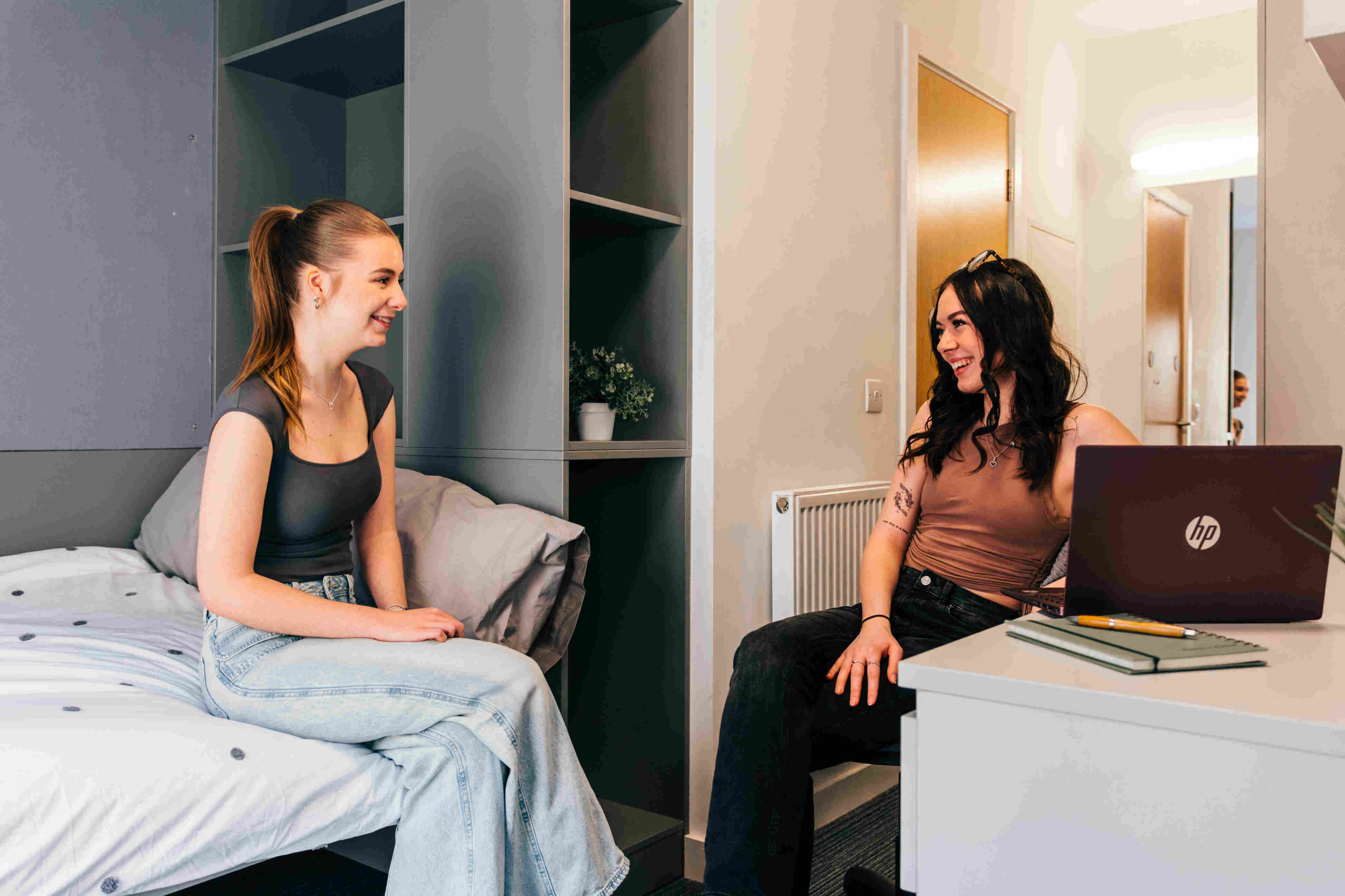 Two students sat opposite in a bedroom, smiling