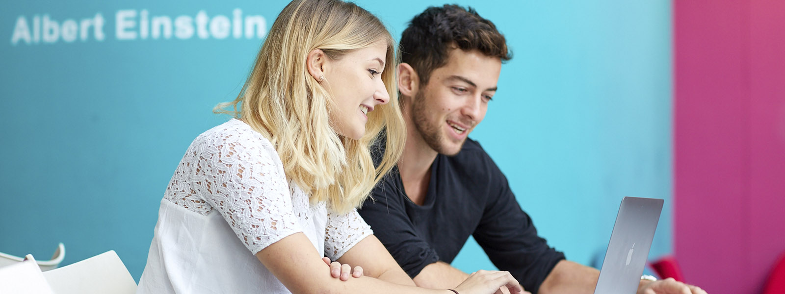 Two students in discussion in front of a laptop